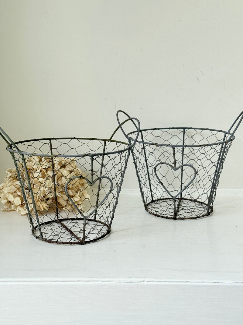 Pair of vintage decorative wire baskets with heart detail and aged patina photographed on a white surface