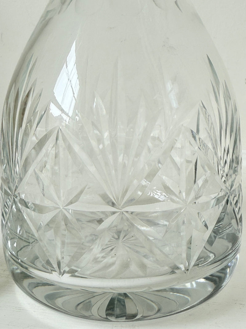 Vintage crystal decanter with faceted stopper and cut glass starburst design, photographed on a white surface