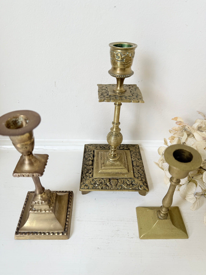 vintage brass trio of candlesticks in mixed designs photographed on white surface