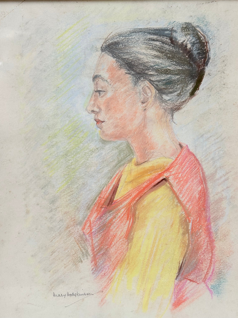 Vintage pastel portrait of a woman in profile wearing red and yellow, framed under glass, photographed on a white surface