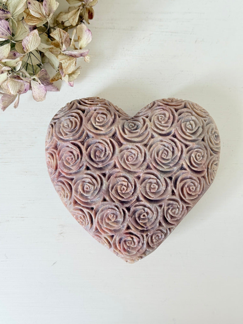 vintage pink stone heart with engraved roses and flat base on white surface