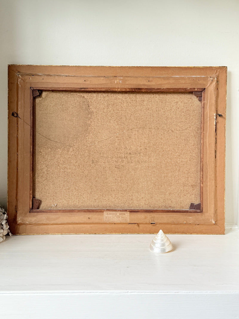 An antique wooden picture frame with a cork backing, displayed on a white shelf against a light beige wall.