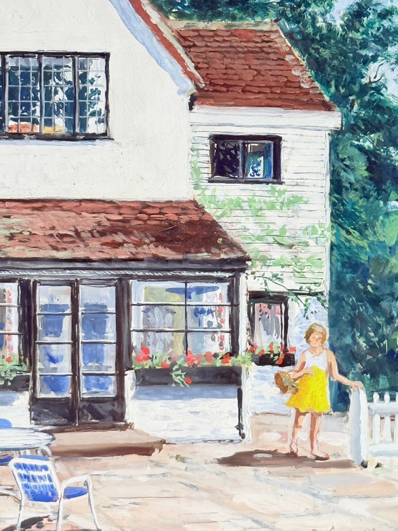 Oil on board painting of a girl in a yellow dress outside a cottage with picket fence, framed, photographed on a white surface