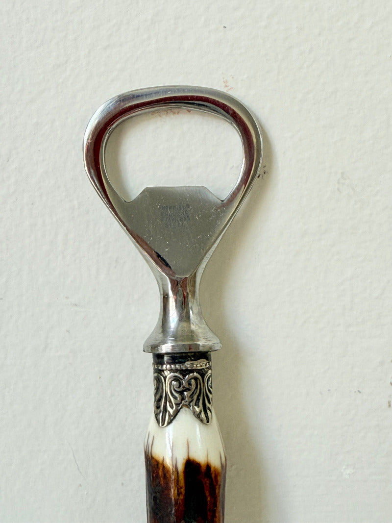 vintage antler handle bottle opener with stainless steel top photographed on white surface