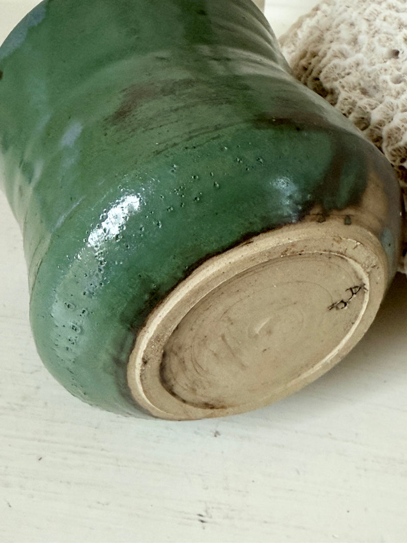 Studio pottery pencil pot in green glaze, handmade on the wheel, photographed on a white surface with pencils inside.
