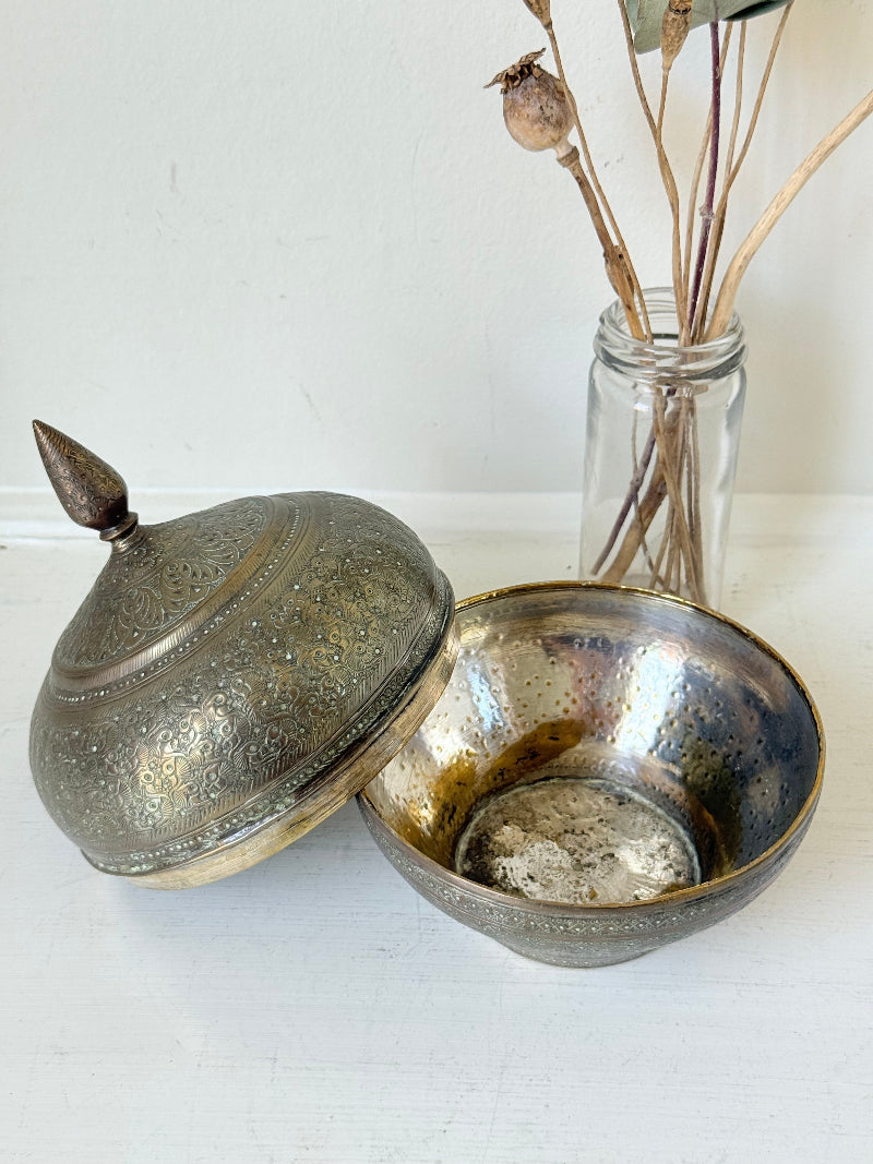 Indian Benares brass lidded jar with floral engraving and finial, photographed on a white surface