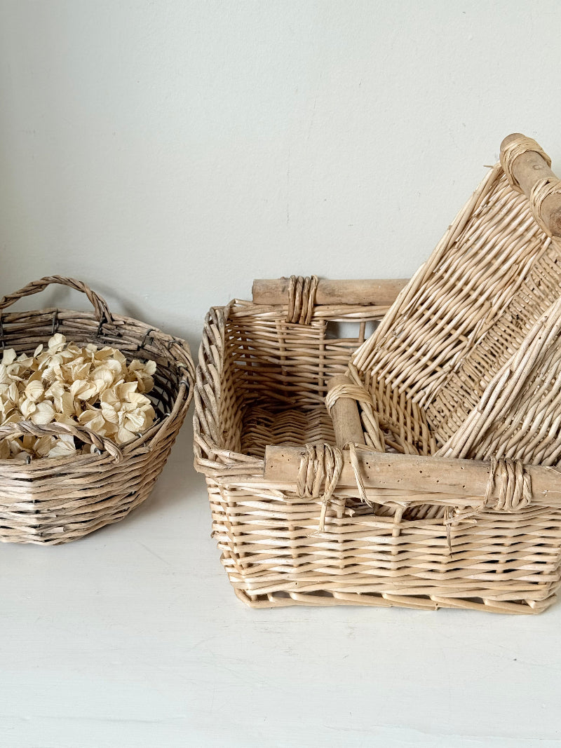 Set of three vintage woven willow baskets in natural tones photographed on a white surface