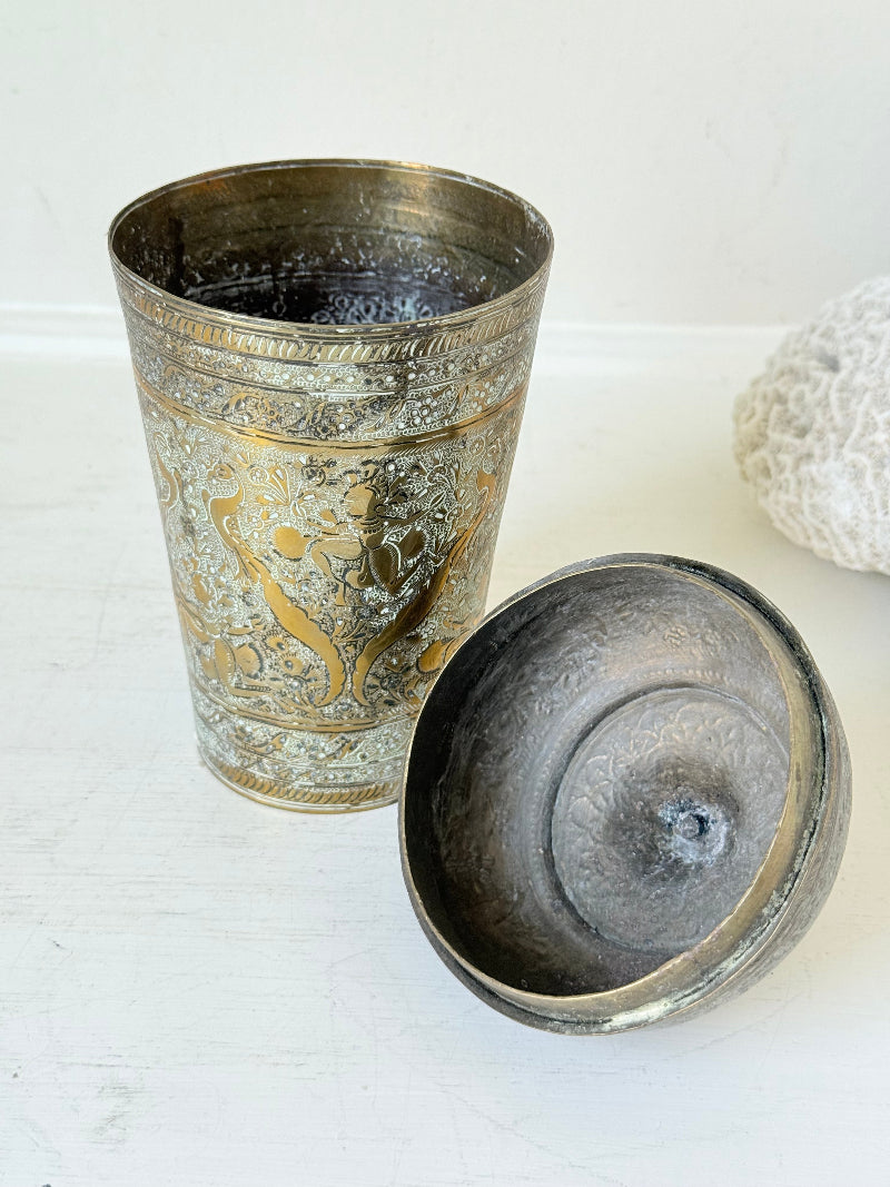 Indian Benares brass jar with lid and engraved animals and floral design, photographed on a white surface