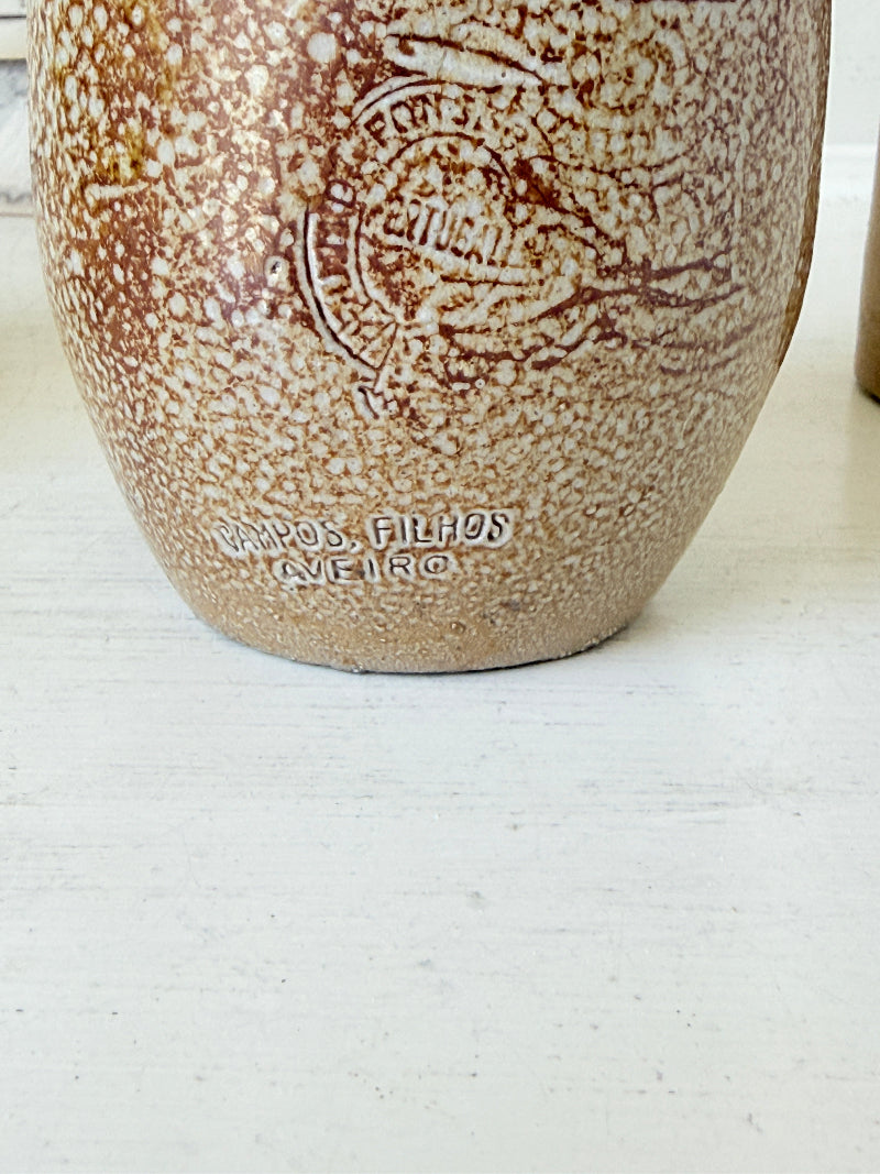 Three antique stoneware bottles, a printed Caley of Norwich and a Portuguese Campos Filhos, photographed on a white surface