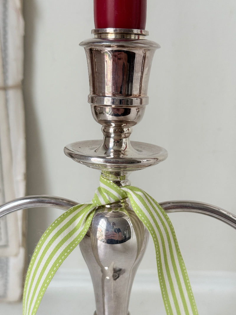 Silver plate three light candelabra with curved arms and domed base holding red taper candles