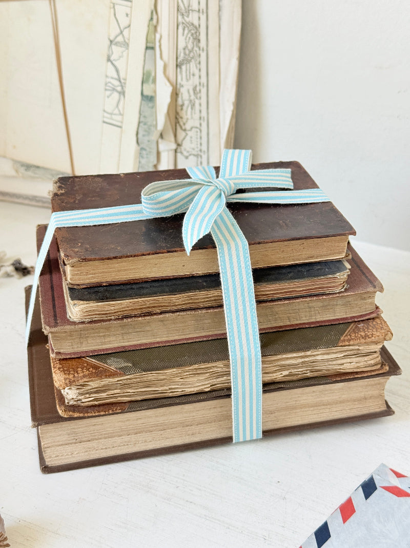 Vintage decorative brown book bundle with aged hardback covers tied with blue stripe ribbon for bookshelf and table styling