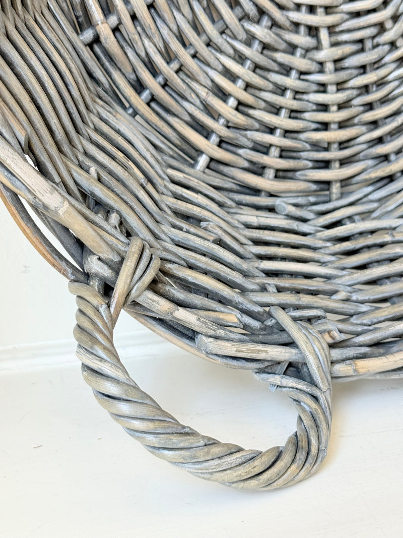 Large vintage woven basket with handles, photographed on a white surface