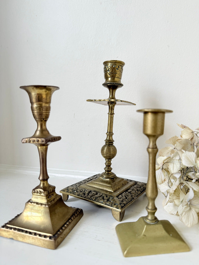 vintage brass trio of candlesticks in mixed designs photographed on white surface
