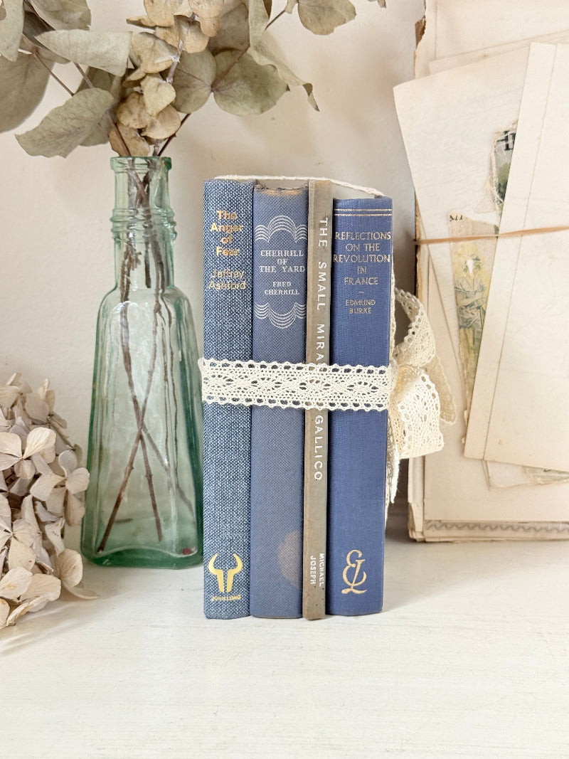 Bundle of vintage blue cloth books with gilt spines tied with ivory lace ribbon for shelf and table styling