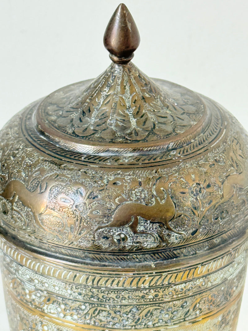 Indian Benares brass jar with lid and engraved animals and floral design, photographed on a white surface