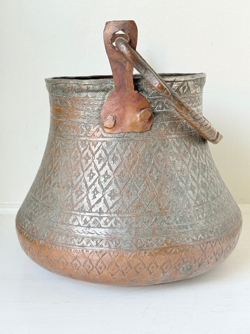 antique Middle Eastern water ewer with engraved diamond and foliate pattern and copper base, displayed on white surface