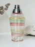 Vintage glass cocktail shaker with multicoloured stripes and silver lid photographed on a white surface.