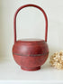 Vintage red painted wooden basket with tall curved handle and domed lid photographed on a white surface