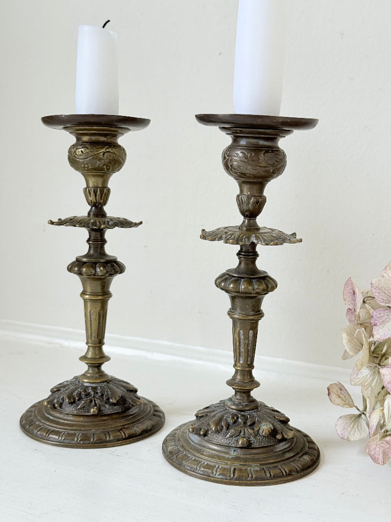 pair of antique brass candlesticks with turned detailing on white surface
