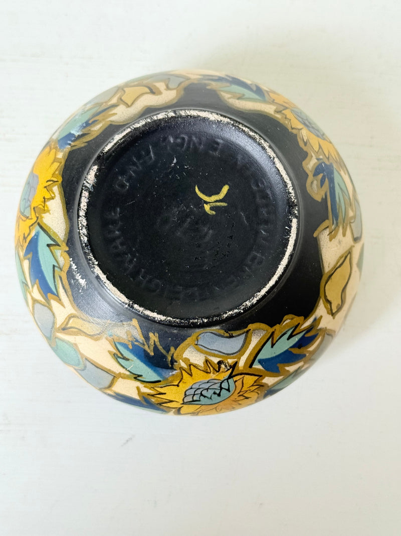 Brentleigh Ware Art Deco pottery jar with hand painted floral decoration on a black ground, photographed on a white surface