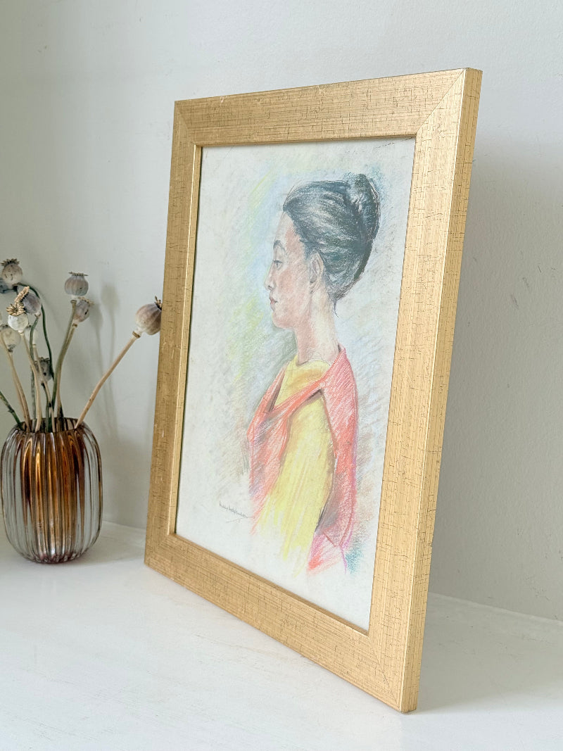 Vintage pastel portrait of a woman in profile wearing red and yellow, framed under glass, photographed on a white surface