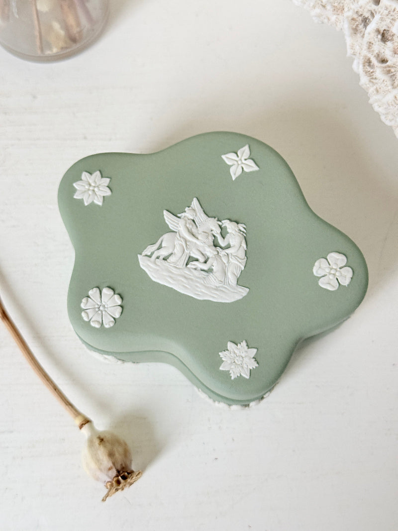 Vintage Wedgwood Jasperware sage green lidded trinket box in a quatrefoil shape, decorated with white neoclassical cherubs and florets, styled with dried stems.
