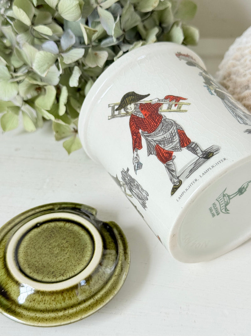 vintage Holkham pottery condiment pot with green lid and illustrated figures photographed on white surface