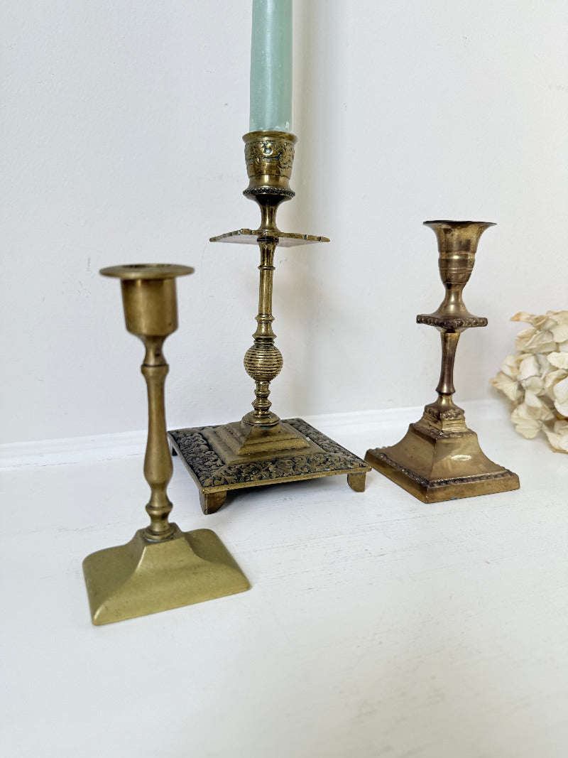 vintage brass trio of candlesticks in mixed designs photographed on white surface