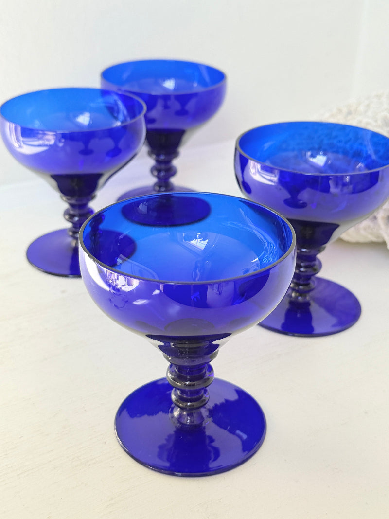 Set of four vintage cobalt blue cocktail glasses with stepped stems, photographed on a white surface