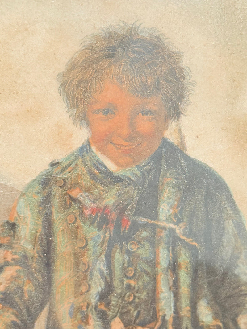 Vintage print of Little Beggar Boy in muted colours, framed under glass in simple wooden frame, on white surface.