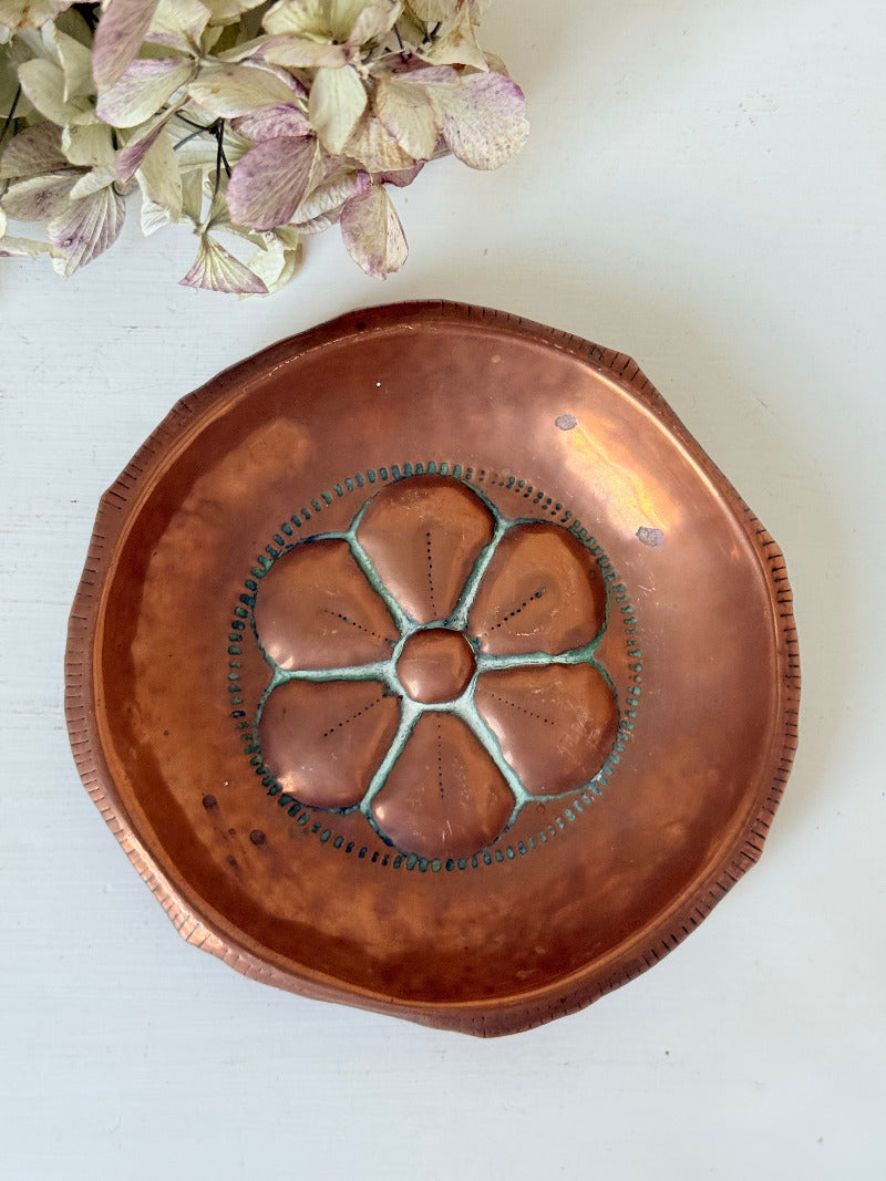small vintage copper dish with cut-out floral centre photographed on white surface