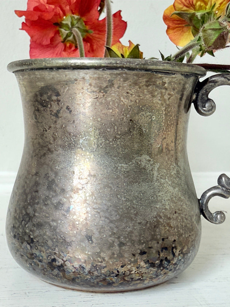 vintage silver plate beaker by arthur price with ornate handle and patina, photographed with red flowers on a white surface