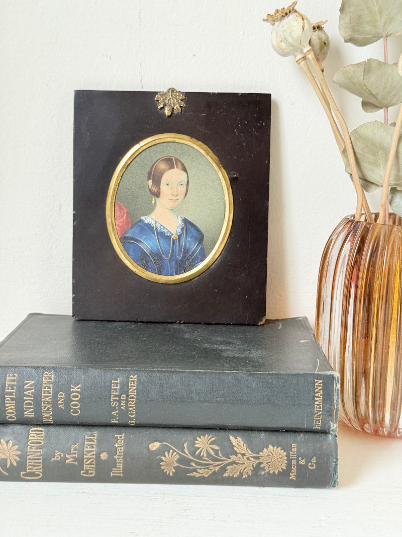 19th century watercolour miniature portrait of woman in blue dress, oval ebonised frame, styled on white background