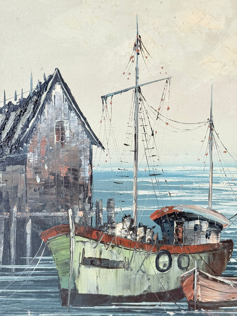 Vintage harbour scene oil painting of fishing boat and wharf buildings in gilt frame, textured brushwork, on white surface.