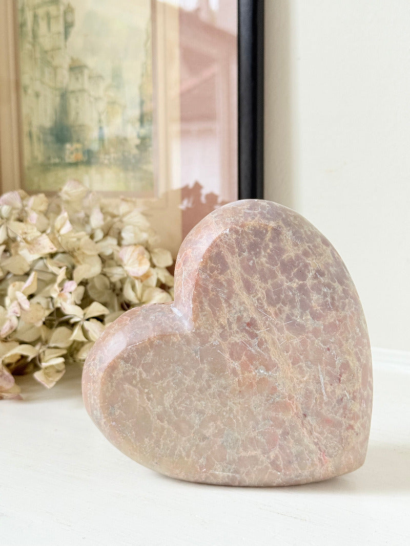 vintage pink stone heart with engraved roses and flat base on white surface