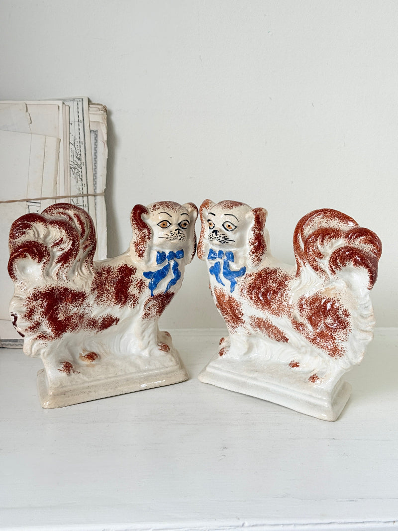 Pair of antique standing Staffordshire Pekingese dogs in rust red and white with blue painted bows