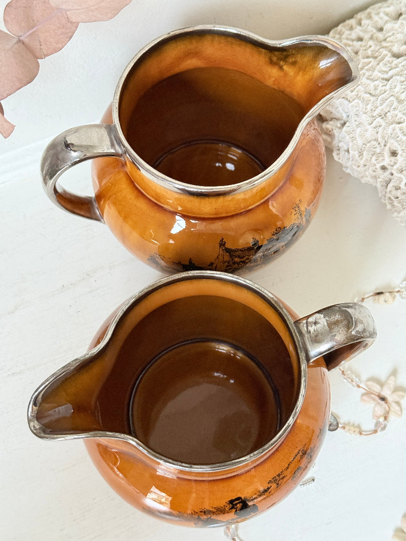 Pair of vintage Ridgways Coaching Days and Coaching Ways treacle jugs in amber brown glaze photographed on a white surface