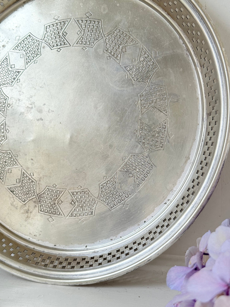Vintage round silver plate tray with brass rim, pierced edge and etched central motif, photographed on white surface
