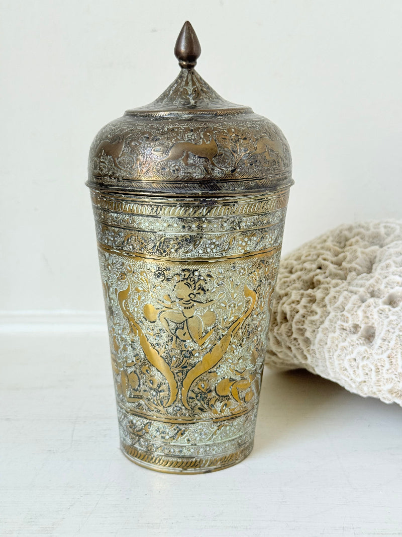 Indian Benares brass jar with lid and engraved animals and floral design, photographed on a white surface