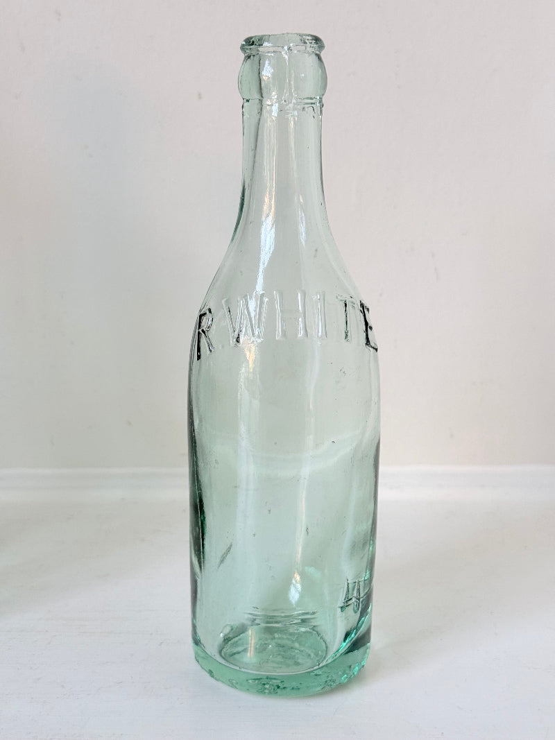 Set of five antique aqua green glass bottles with embossed lettering, photographed on a white surface