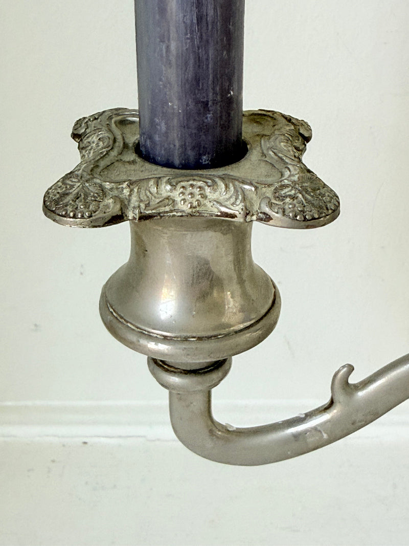Vintage silver coloured three-arm candelabra with ornate base and soft patina, photographed on a white surface