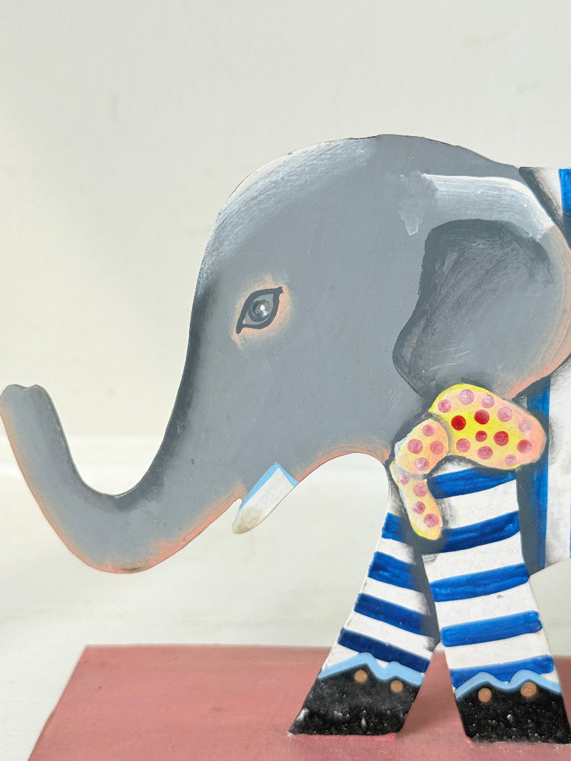 Hand painted metal elephant candlestick in circus-style decoration with colourful patterns, photographed on a white surface