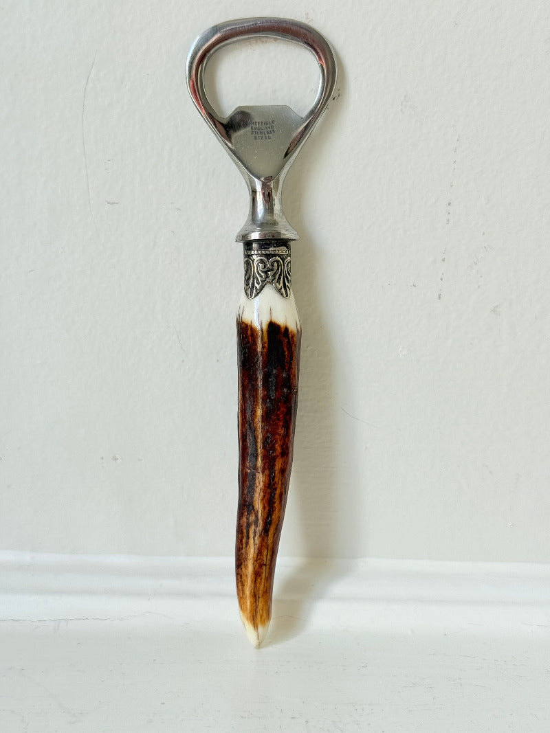 vintage antler handle bottle opener with stainless steel top photographed on white surface