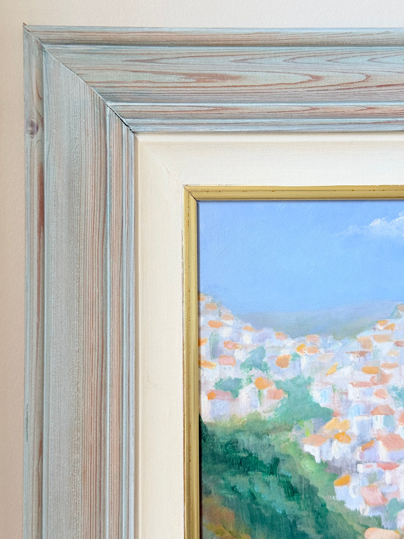 Framed oil painting of Costa del Sol with whitewashed hillside towns, photographed on a white surface