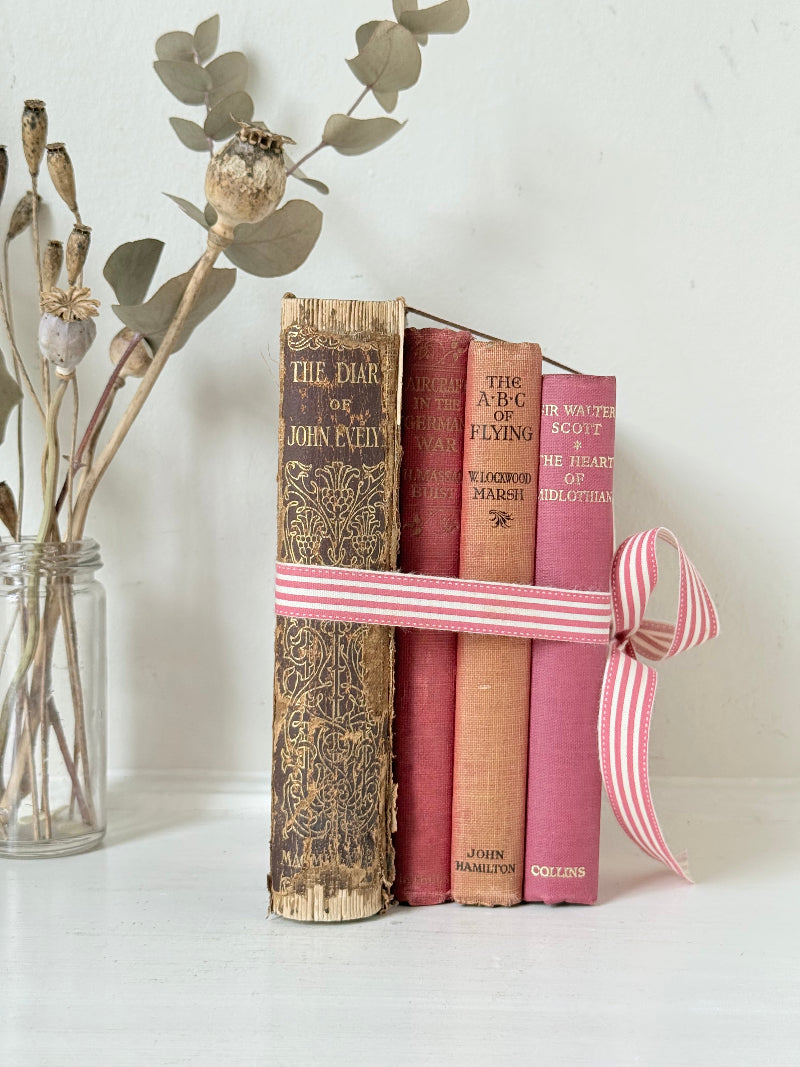 Vintage autumn colours decorative book bundle with pink ribbon, photographed on a white surface