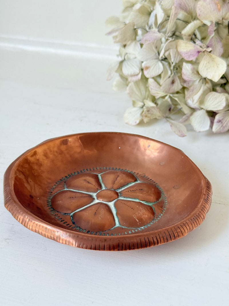 small vintage copper dish with cut-out floral centre photographed on white surface