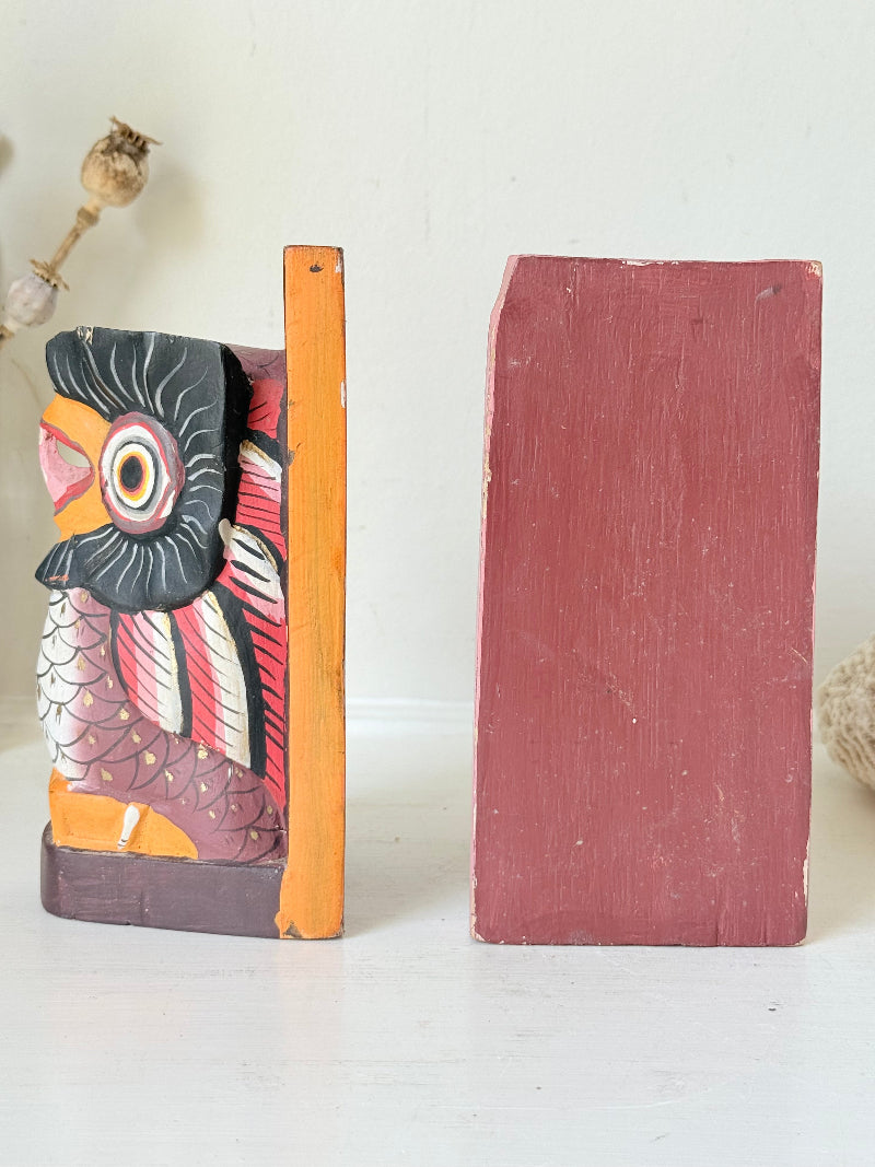 Vintage wooden owl bookends hand painted in red and orange tones, displayed on a white surface beside dried flowers.