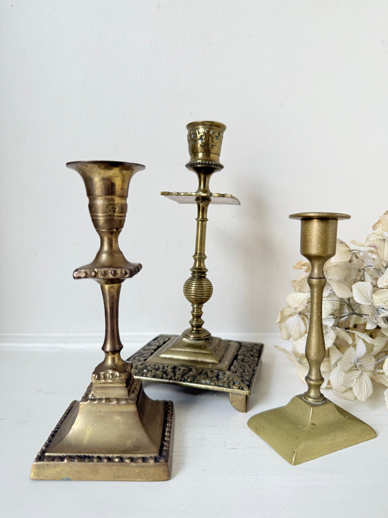 vintage brass trio of candlesticks in mixed designs photographed on white surface