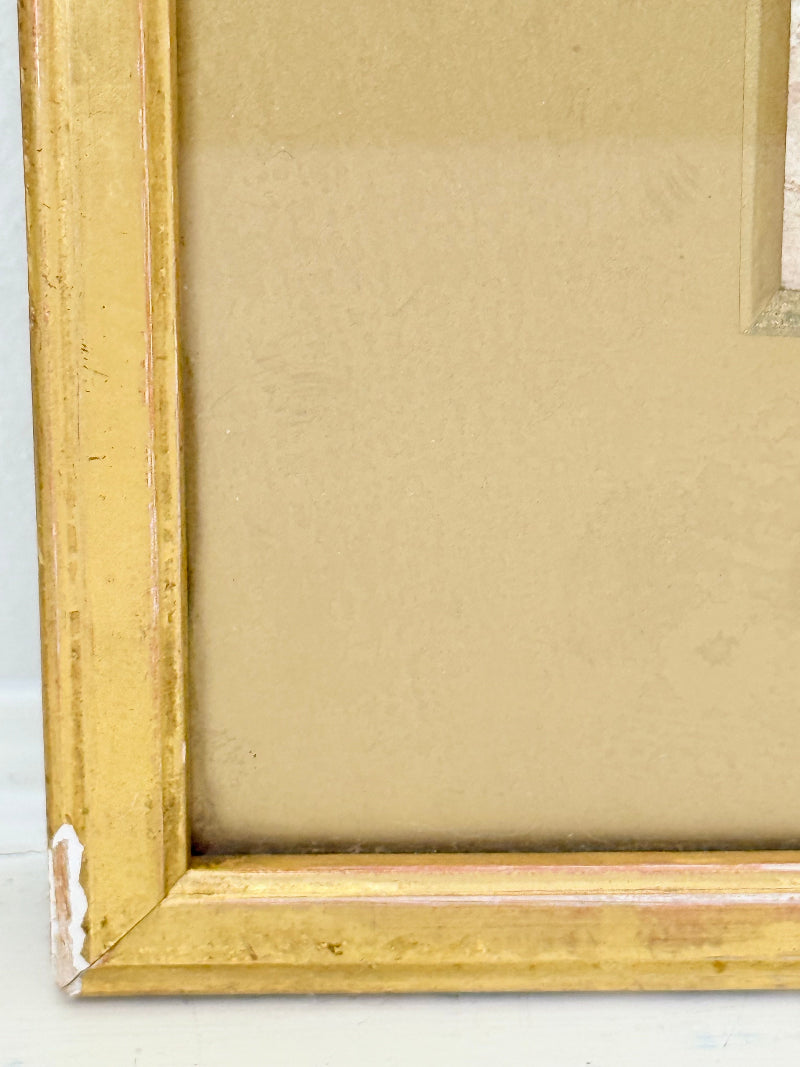 Framed vintage watercolour of countryside farm buildings with red roofs in gold frame photographed on a white surface