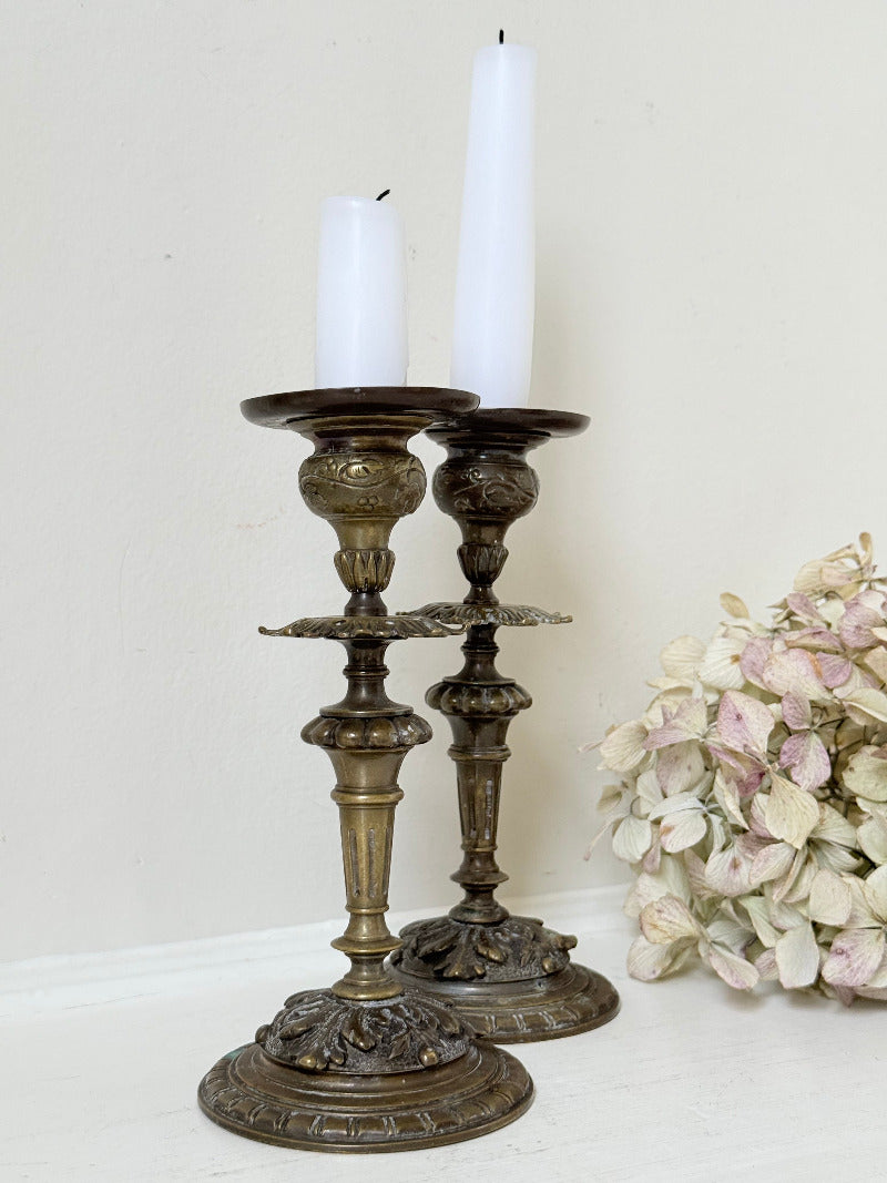 pair of antique brass candlesticks with turned detailing on white surface